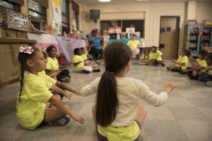 A group of second graders sit in a circle and play a game of Duck-Duck-Goose.