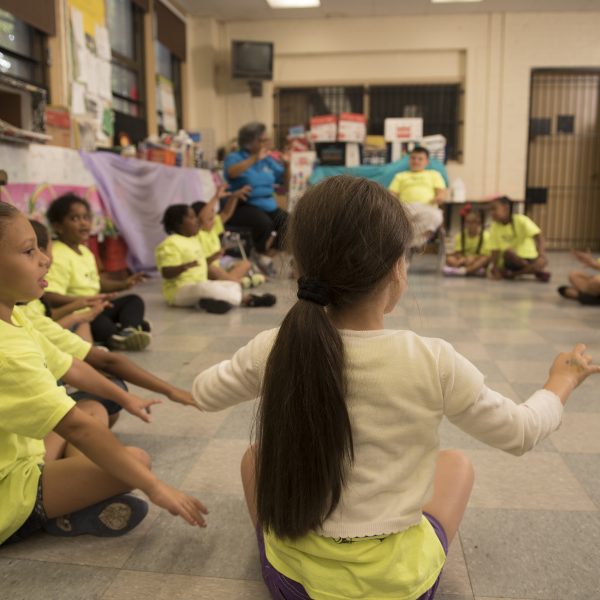 A group of second graders sit in a circle and play a game of Duck-Duck-Goose.